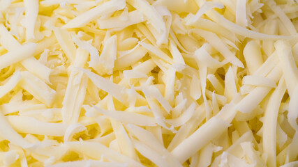 Grated cheese close-up, background. Delicious hard cheese grated on a grater