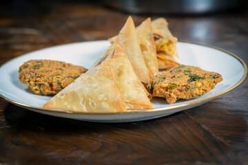 A group of Indian tea-time snacks, including samosa and vada, on a plate.