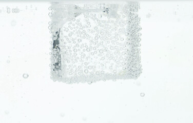 Refreshing soda water with ice cube in glass against white background, closeup