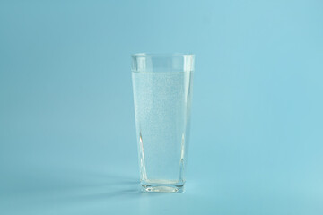 Soda water in glass on light blue background