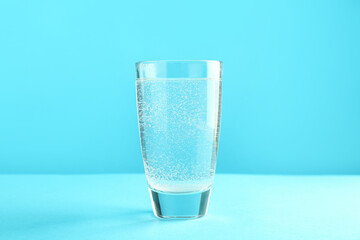 Soda water in glass on light blue background