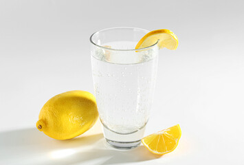 Refreshing soda water in glass and lemon on light grey background
