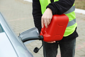 Man with canister refueling car outdoors, closeup