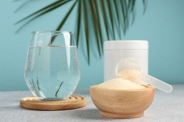 Collagen powder and glass of water on grey textured table against light blue background, closeup