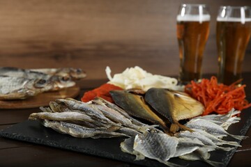 Dried fish snacks and beer on wooden table, closeup