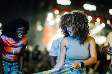 Young women dancing and laughing at music festival at night