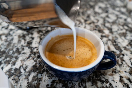Pouring Milk Into a Cup of Espresso Coffee
