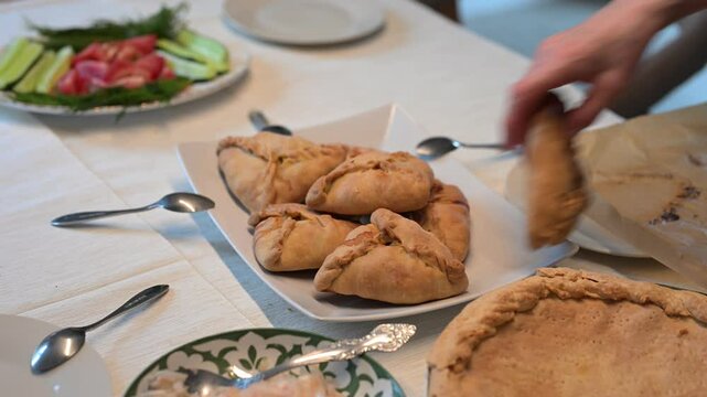Hot echpochmak pies. Placing a traditional tatar small triangle pies on a white plate. Traditional tatar cuisine