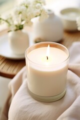 Burning candle on white fabric, closeup.