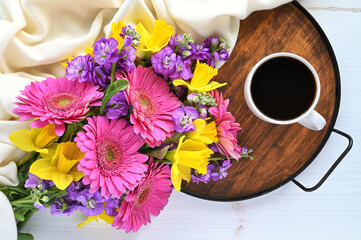 Colorful spring bouquet and a cup of coffee or hot tea on a tray