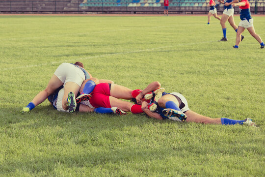 Professional rugby player is blocked by the opposite team player on ground. Rugby players striving to get to the ball during the match