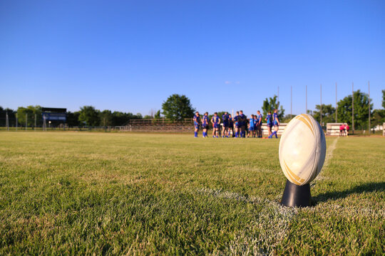 Close up of an rugby football on the field, players in the background