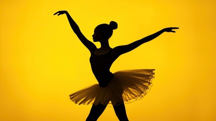 Silhouette of ballet dancer posing gracefully in tutu against bright yellow background in studio