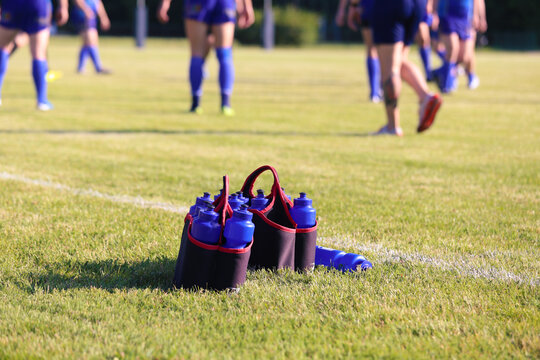 Sport bottles of fresh water energy drink on football rugby field grass