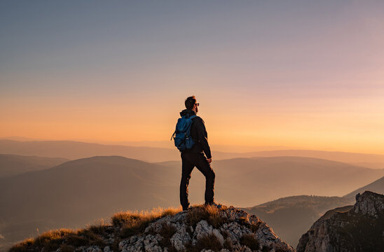 A man who hikers enjoys a break look at the top of the mountain at sunset adventure travel.