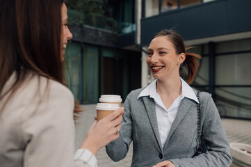 Businesswomen talking and holding disposable coffee cups outdoors