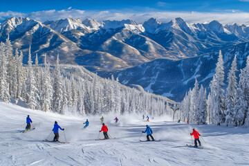 Exhilarating Alpine Descent: Skiers Carving Through Pristine Powder with Majestic Peaks in the Backdrop