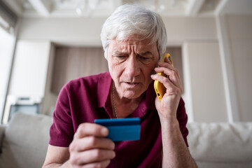 Trusting serious feared pensioner giving away card number to fraudsters over phone. Financial scam,...