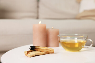 Palo santo sticks, burning candles and tea on white table indoors
