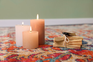 Palo santo sticks and burning candles on rug indoors, space for text