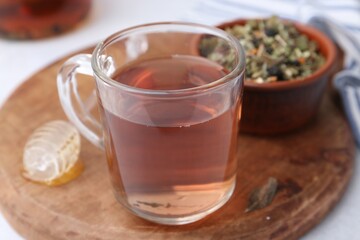 Delicious herbal tea, honey and dry leaves on white table, closeup