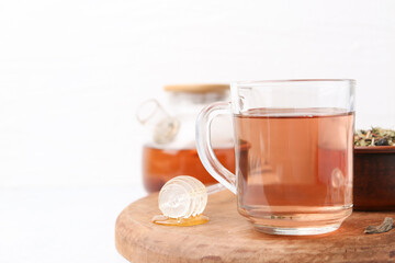 Delicious herbal tea, honey and dry leaves on white table. Space for text