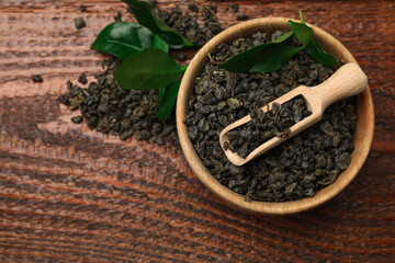 Dried and fresh tea leaves on wooden table, top view