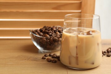 Coffee cream liqueur in glass and beans on wooden table, closeup. Space for text