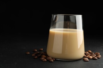 Coffee cream liqueur in glass and beans on black table, space for text