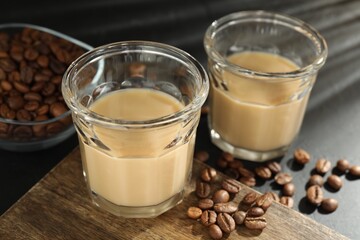 Coffee cream liqueur in glasses and beans on table, closeup