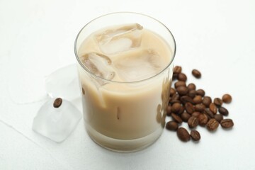 Coffee cream liqueur in glass, ice and beans on white table, closeup