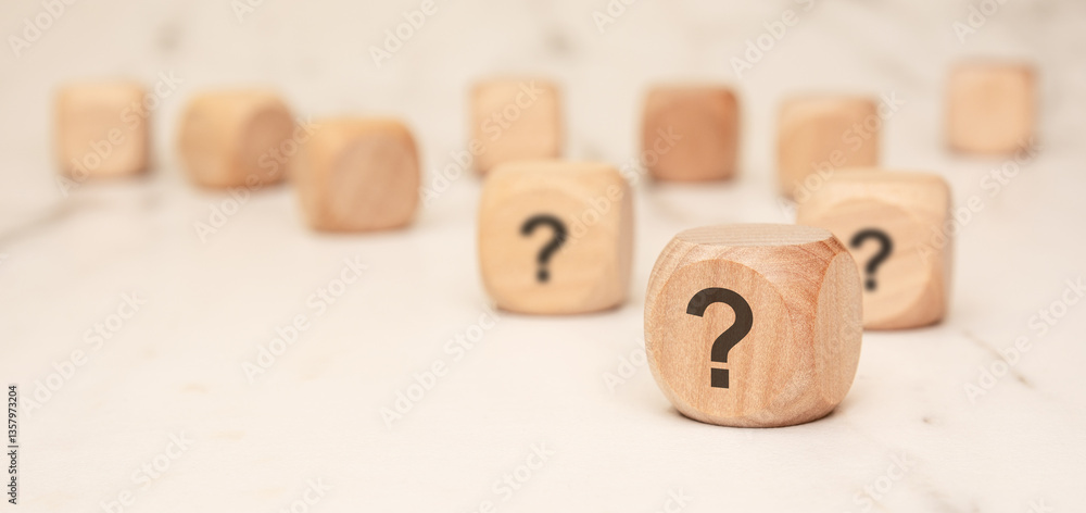 Poster wooden blocks with question marks on a marble surface, symbolizing uncertainty and curiosity