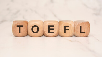 wooden blocks spelling out 'TOEFL' symbolize education constraints