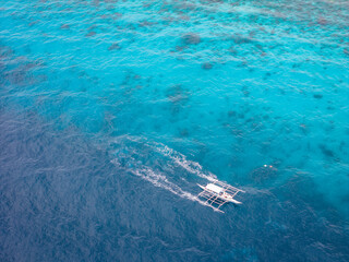 Close up of traditional Philippine island hopping boat in turquoise color water. Aerial top view...