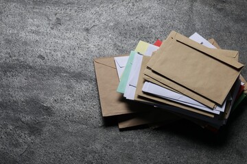 Post office. Stack of different paper envelopes on dark grey table, above view. Space for text
