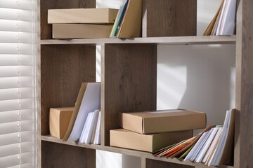 Different paper envelopes and parcels on wooden shelves in post office