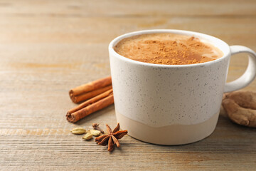 Aromatic Masala tea in cup and spices on wooden table, closeup. Space for text