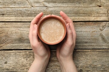 Woman with aromatic Masala tea at wooden table, top view