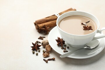 Aromatic Masala tea in cup and spices on light grey table, closeup. Space for text