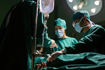 emergency doctor group working using tools to save people. specialist surgical team performing medical tools procedure. medical staff team wearing uniform helping patient in surgery with equipment