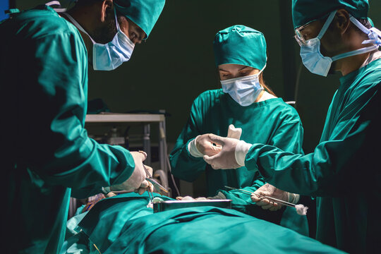 surgeon team using procedure cleaning wound after operating with instruments. surgical group using cotton cleaning injured part. medical staff team wearing uniform working with emergency equipment