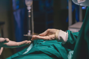 nurse giving professional doctor medical scissors during operating in emergency room. er staff help hand metal equipment scissors to doctor. surgeon get scissors tools to use in procedure from staff