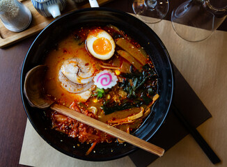 Traditional japanese noodle soup with shiitake mushroom, egg and greens served in ceramic bowl with wooden chopsticks. High quality photo