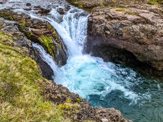 Waterfall cascading into a turquoise pond in Iceland