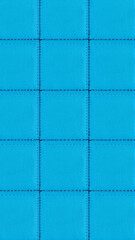 Fototapeta premium The surface texture of artificial leather is blue, the surface is stitched in the form of diamonds, squares, rectangles. Eco-leather in a kilt. 
