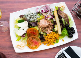 Appetizing salad with tuna, cheese, corn, tomatoes and olives