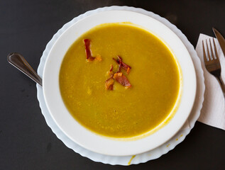 Healthy vegetable cream soup with ham slices served in white plate