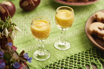 Two shot glasses of Eiecognac with dyed Easter eggs and spring flowers