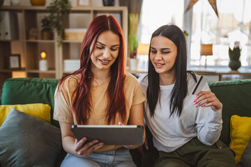 women two females sisters hold credit card online shopping at home