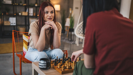 two women young females sisters friends play chess board game at home